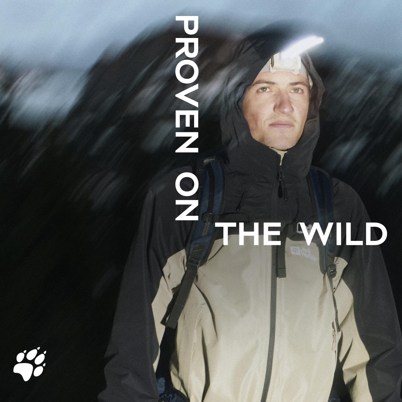 Iemand in een capuchonjack staat 's nachts in de buitenlucht en draagt een hoofdlampje. De tekst luidt "Proven on the Wild“