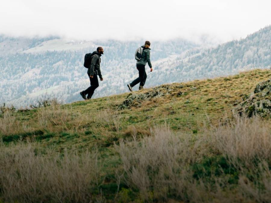 Twee personen in najaars-wandelkleding wandelen over een berg