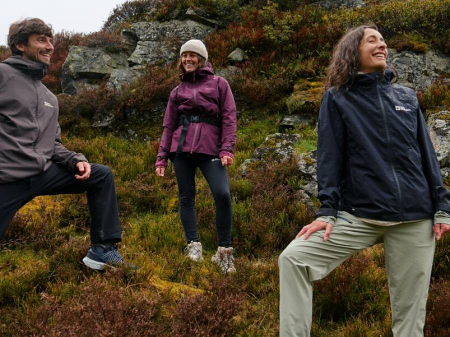 Drie vrienden staan vrolijk kijkend op een bergachtig terrein en kijken in de verte
