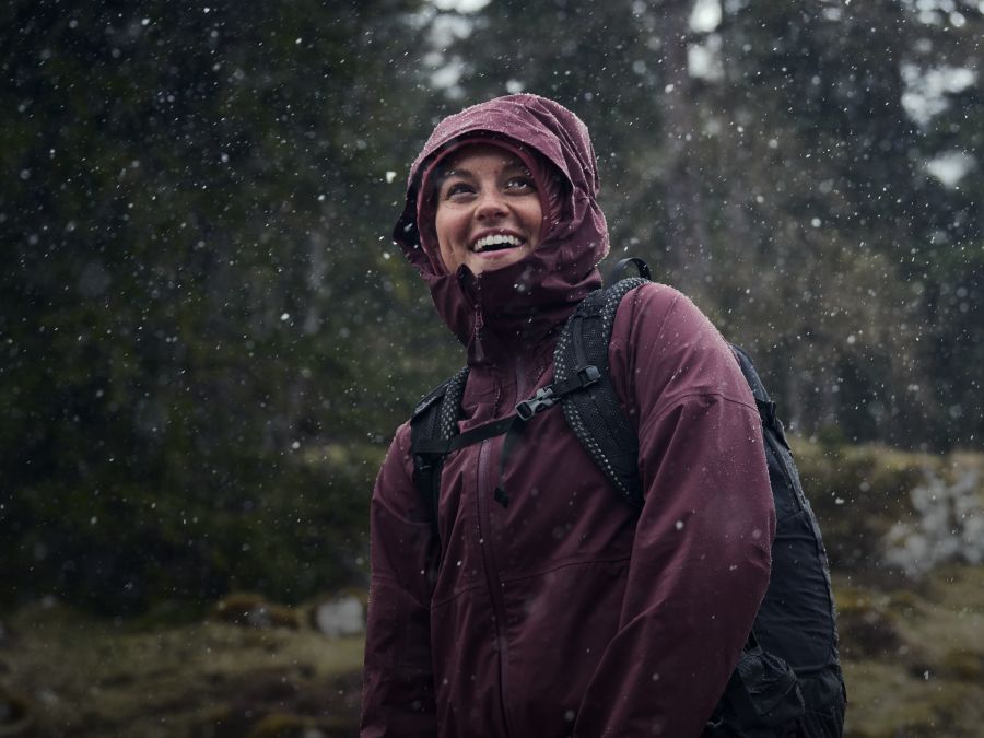 Een vrouw met een regenjas in de regen in het bos