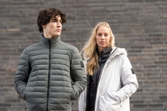 Een vrouw en een man in casual winterjassen voor een muur