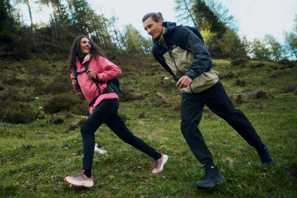 Man en vrouw in sportieve wandelkleding steken een open plek over
