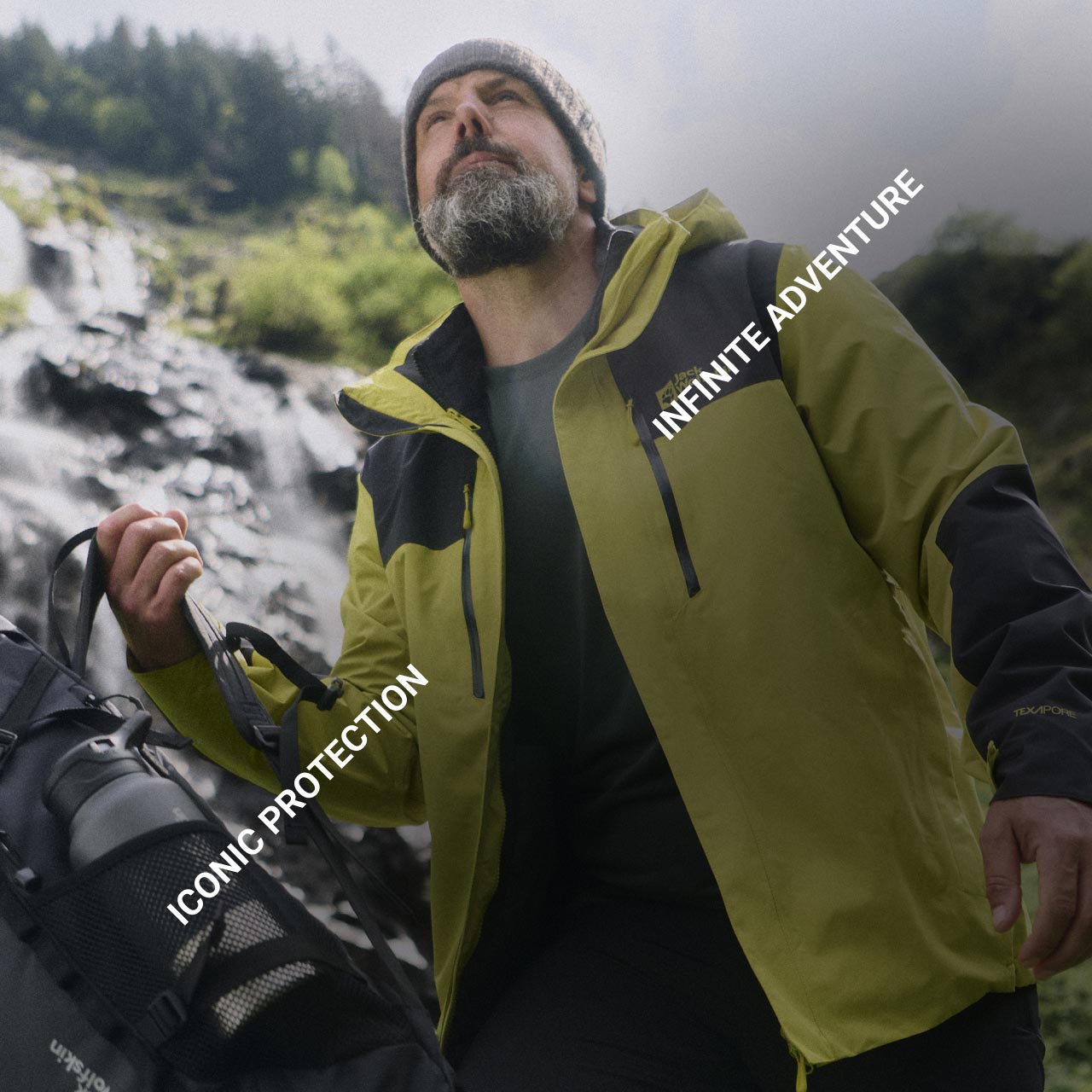 Een man in een geel jack en met een beige muts staat met een rugzak buiten en kijkt naar boven. De tekst luidt: "Iconic Protection" en "Infinite Adventure"