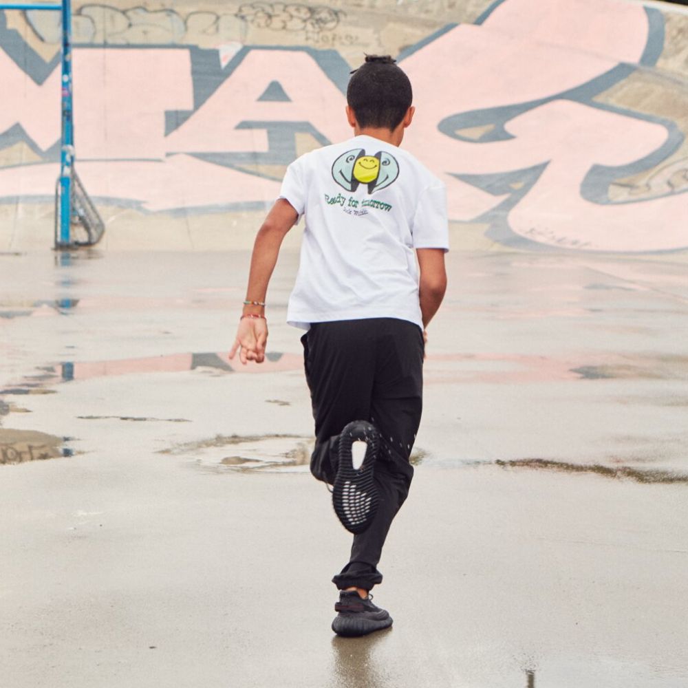 Jongen loopt op asfalt met graffiti op de achtergrond