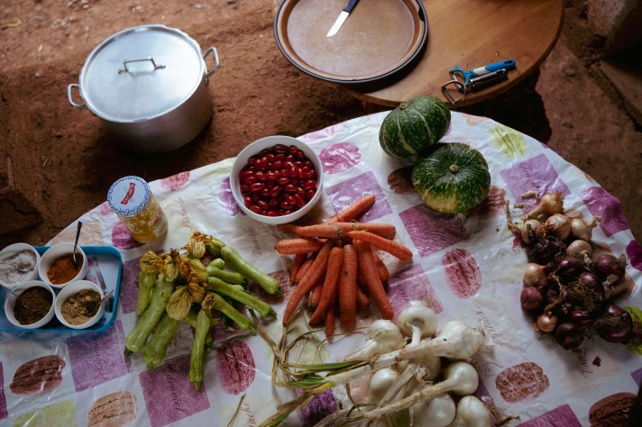 Groenten en specerijen op een tafel met een vrolijk gekleurd tafellaken