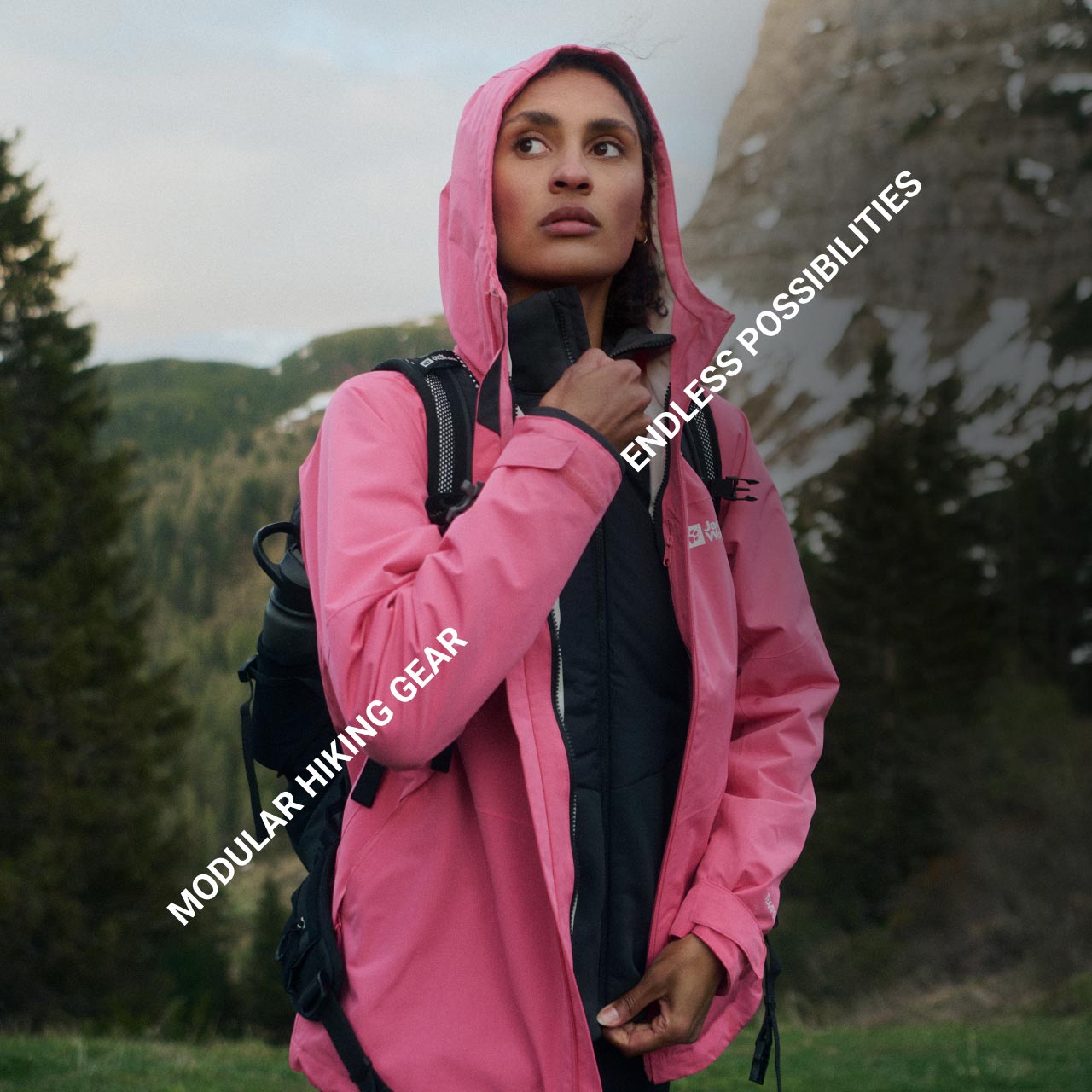 Iemand in een roze jack staat in een bergachtig bosgebied en is in gedachten verzonken. De tekst luidt: "Modular Hiking Gear" en "Endless Possibilities"