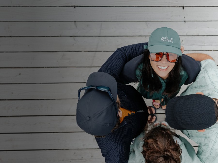 Twee sleeën met elk twee personen glijden een besneeuwde helling af. De&nbsp;mensen lachen en dragen winterkleding, mutsen en zonnebrillen; op de&nbsp;achtergrond zijn met sneeuw bedekte bergen te&nbsp;zien.